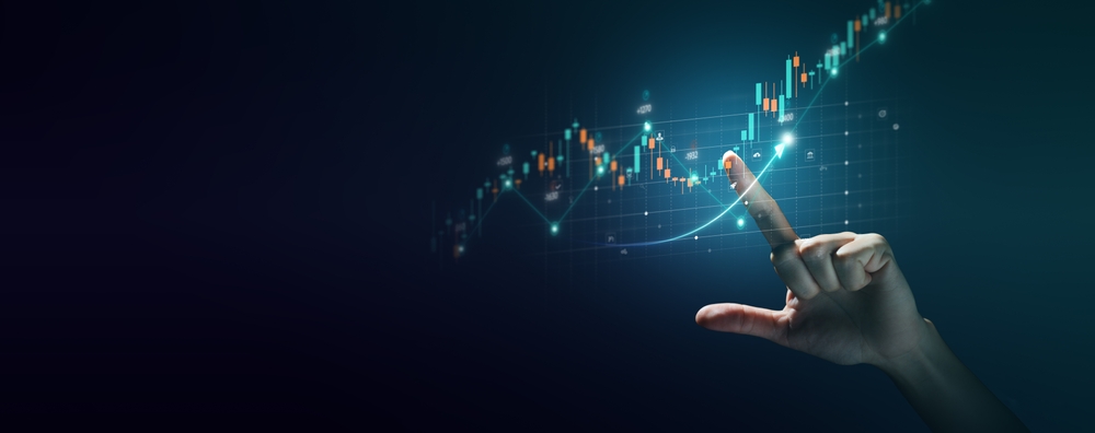 A hand interacting with a futuristic digital stock market graph, showcasing rising candlestick charts and financial data visualization on a dark blue background. The image represents data analytics, market trends, and financial growth.